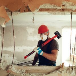 builder-with-hammer-his-hands-breaks-cement-wall