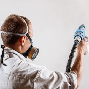 worker-painting-wall-with-spray-gun-white-color